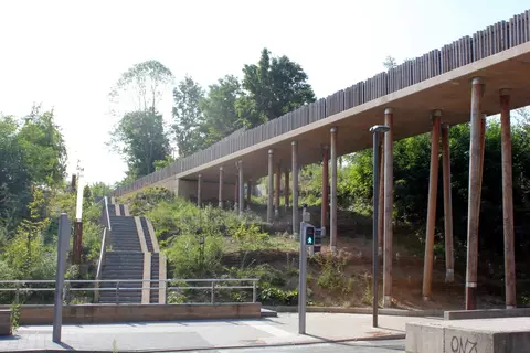 un jeu de pieux en bois rond couronnés d'une fine dalle de béton instaure un rythme, une direction, un mouvement.